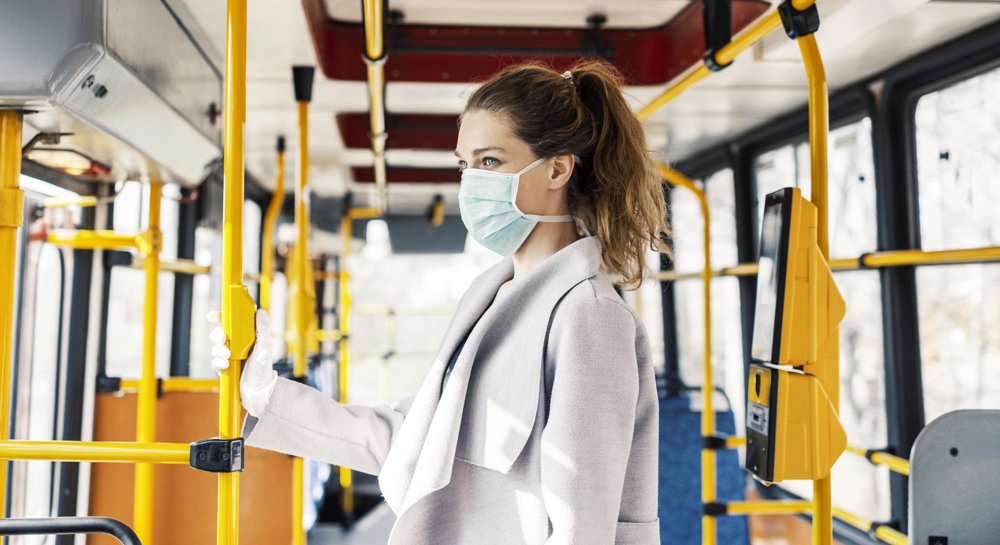 Woman wearing a mask on a bus.