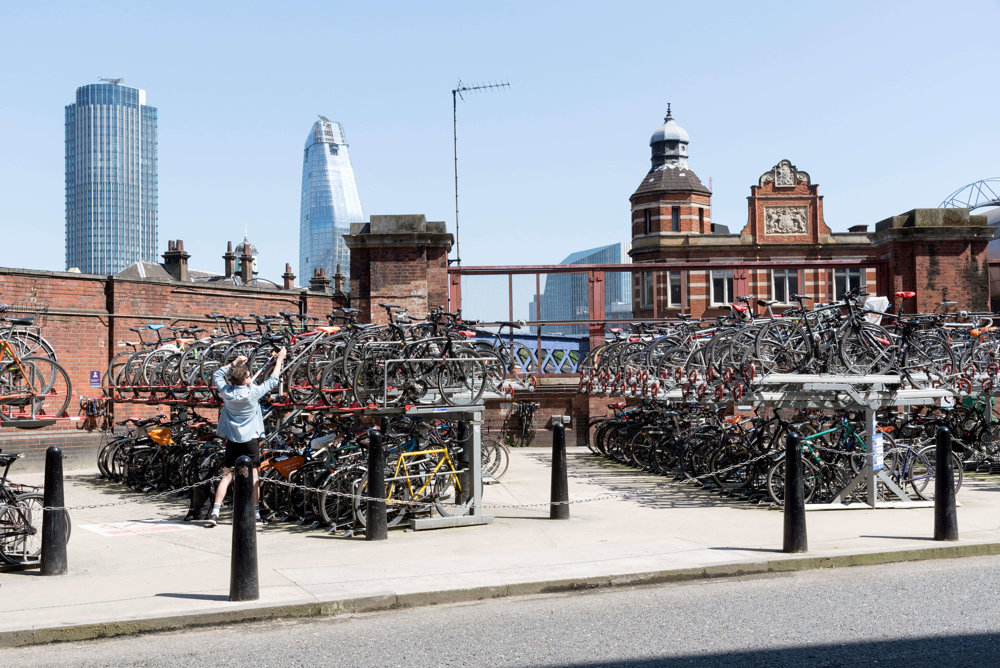 Bike storage area in London with man locking up his bike.